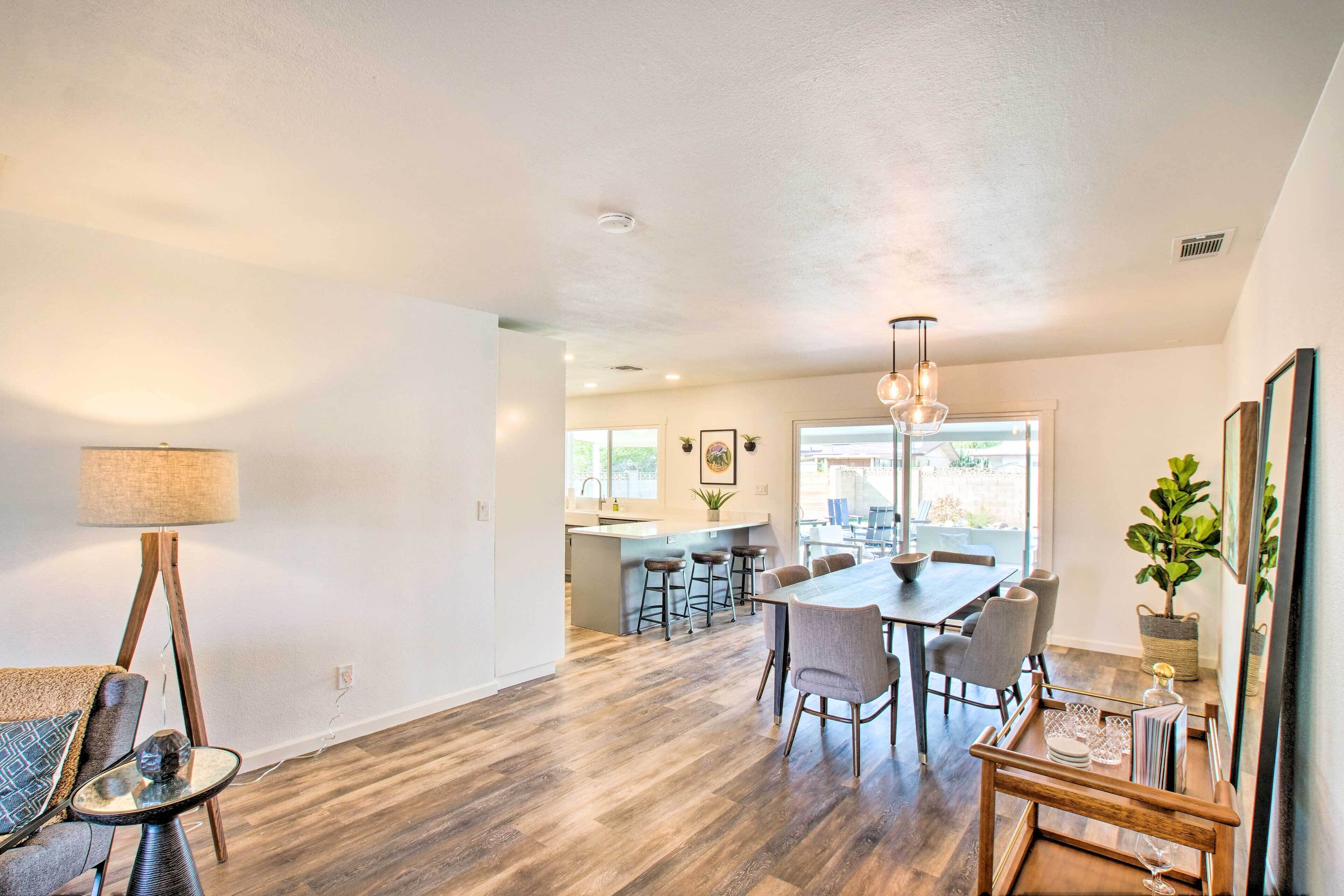 A modern kitchen with a central island, bar stools, and a dining table with chairs.