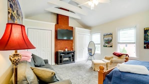 A cozy room with a fireplace, a TV mounted on the wall, a bed with a blue quilt, and a red lamp. - Walk to Walnut St: Pet-friendly Pittsburgh Home! (Pittsburgh)