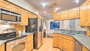 A modern kitchen with wooden cabinets, stainless steel appliances, and a granite countertop. - Lake Placid Paradise w/ Dock, Grill & Kayaks! (Seguin)