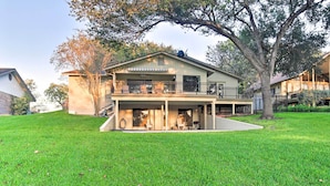 A two-story house with a covered front porch, a large lawn, and a tree. - Lake Placid Paradise w/ Dock, Grill & Kayaks! (Seguin)