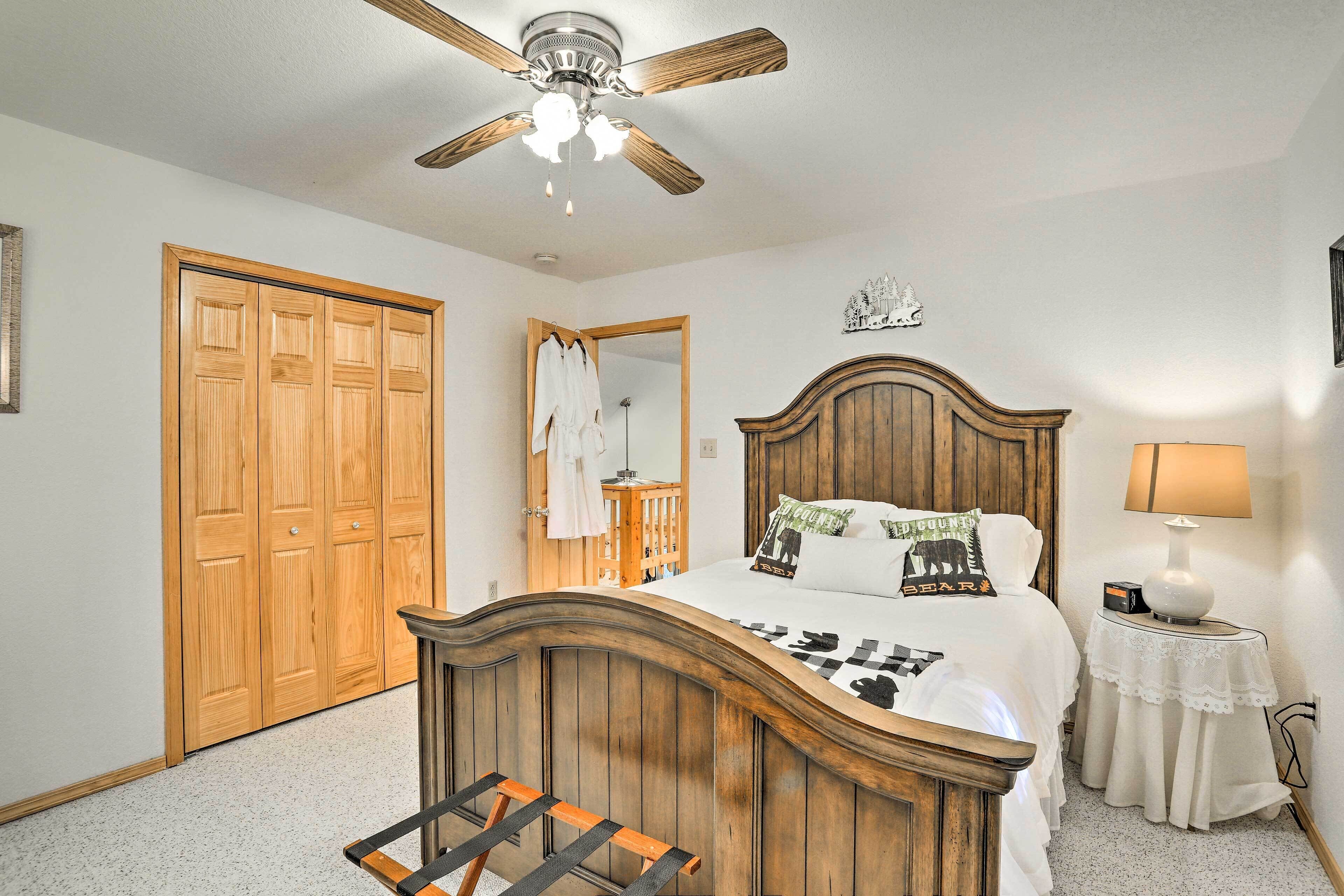 A bedroom with a wooden bed, a ceiling fan, a nightstand with a lamp, and a wardrobe.
