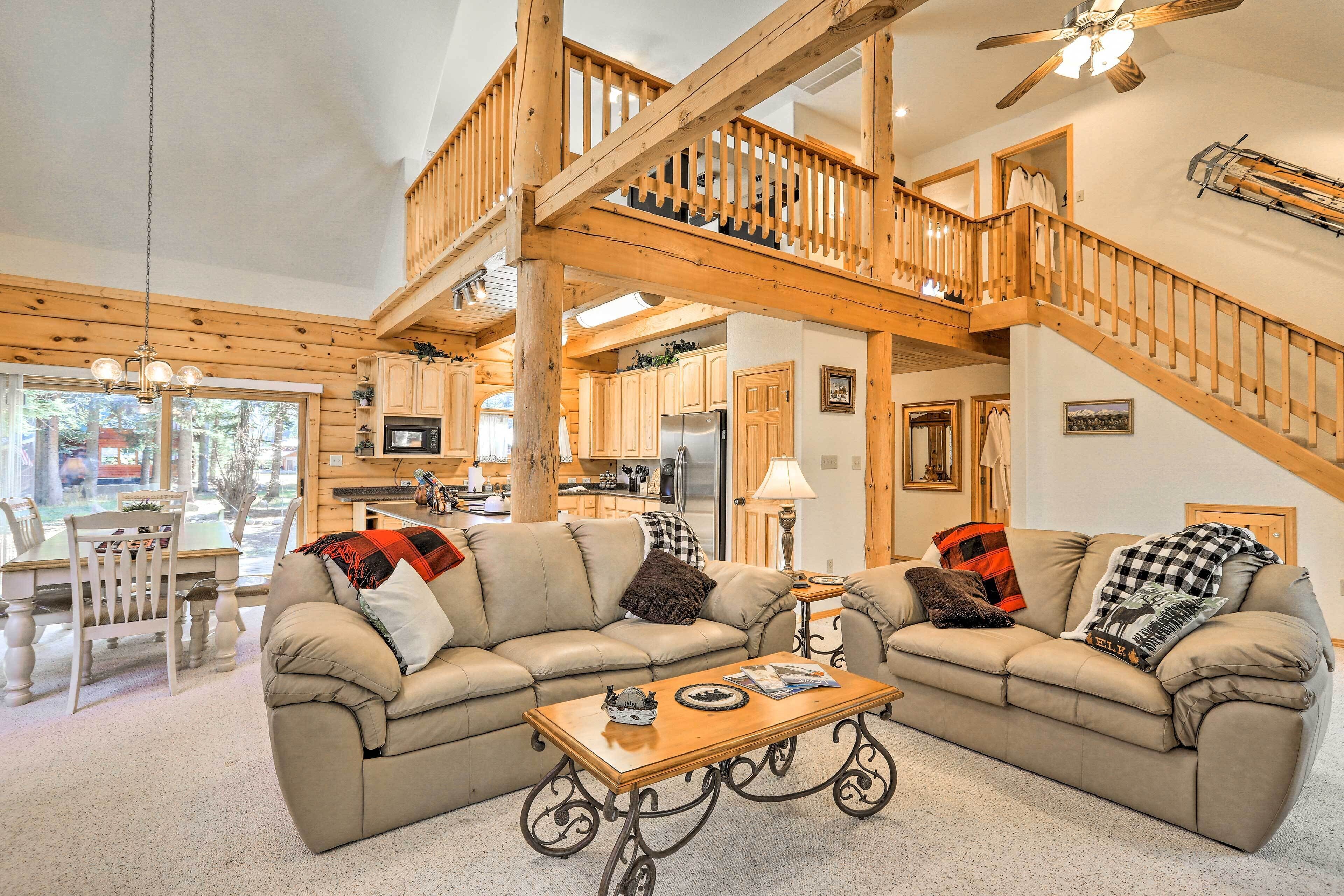 Un vaste espace de vie agrémenté d’un grand escalier en bois, d’un grand canapé d’angle beige et d’une table basse en bois.