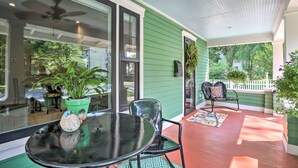 A covered porch with a glass door, a ceiling fan, and a table with chairs.