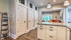 A kitchen with white cabinets, a granite countertop, and a black pot rack.