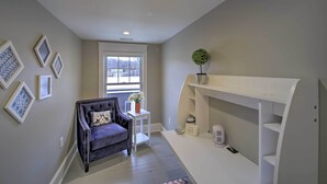 A modern living room with a dark blue sofa, a white side table with a vase of flowers, and a white shelving unit with decorative items.