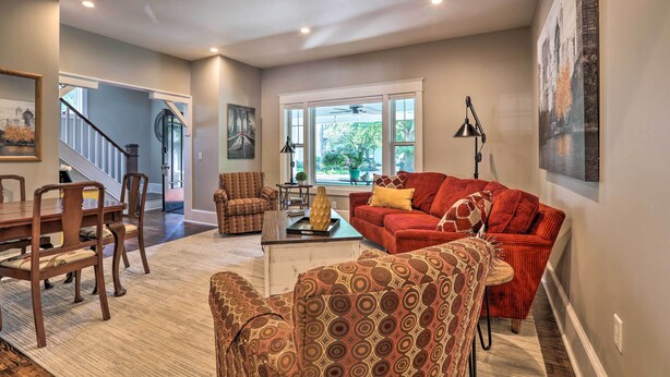 A spacious living room with a dining area, a staircase, and large windows.