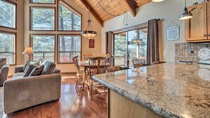 A spacious kitchen with large windows, a dining area with wooden chairs, and a granite countertop. - Pet-friendly Munds Park Retreat w/ Wraparound Deck (Munds Park)