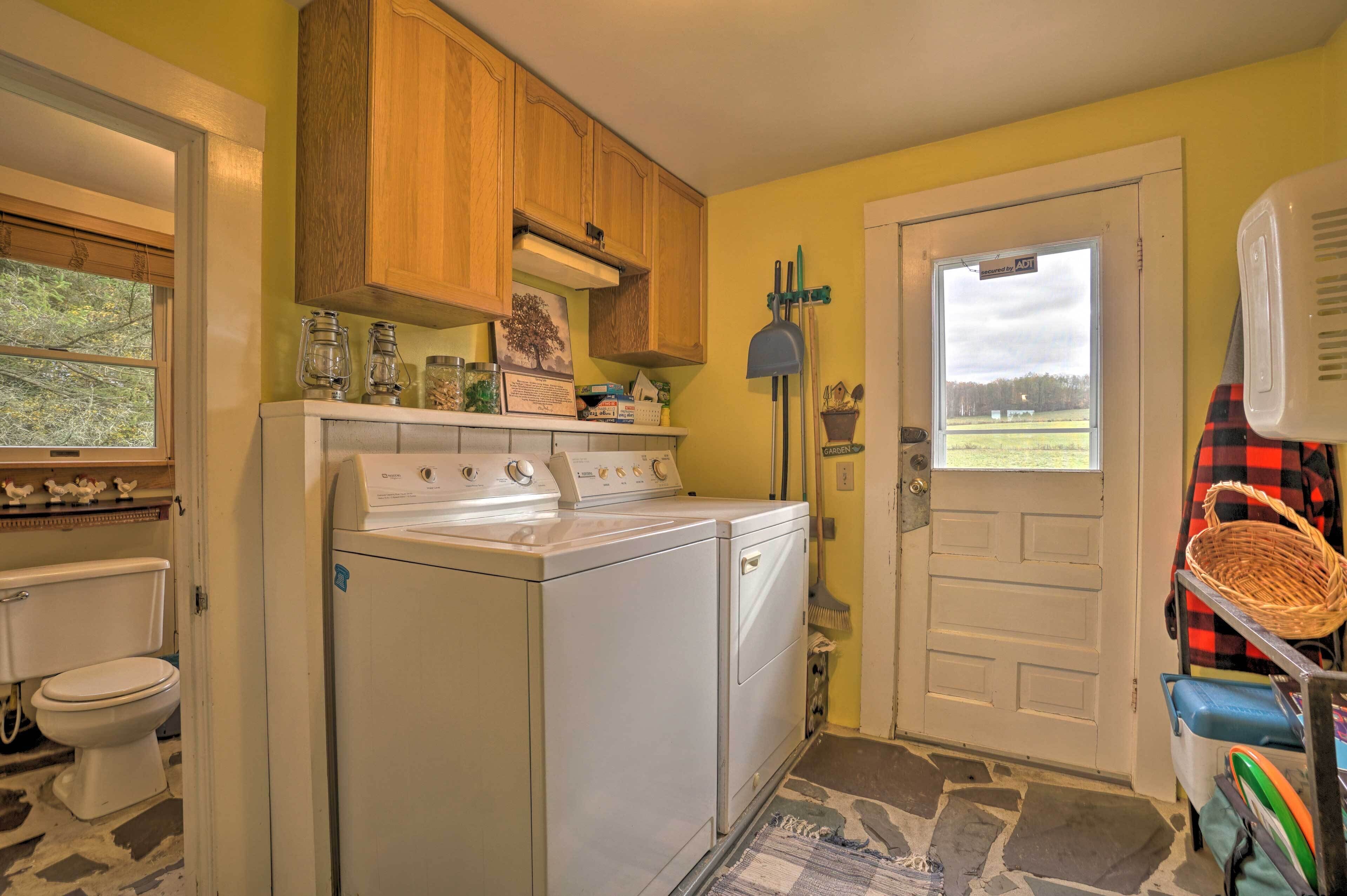 A laundry room with a washer and dryer, wooden cabinets, a window, and a door with a view of the outdoors.