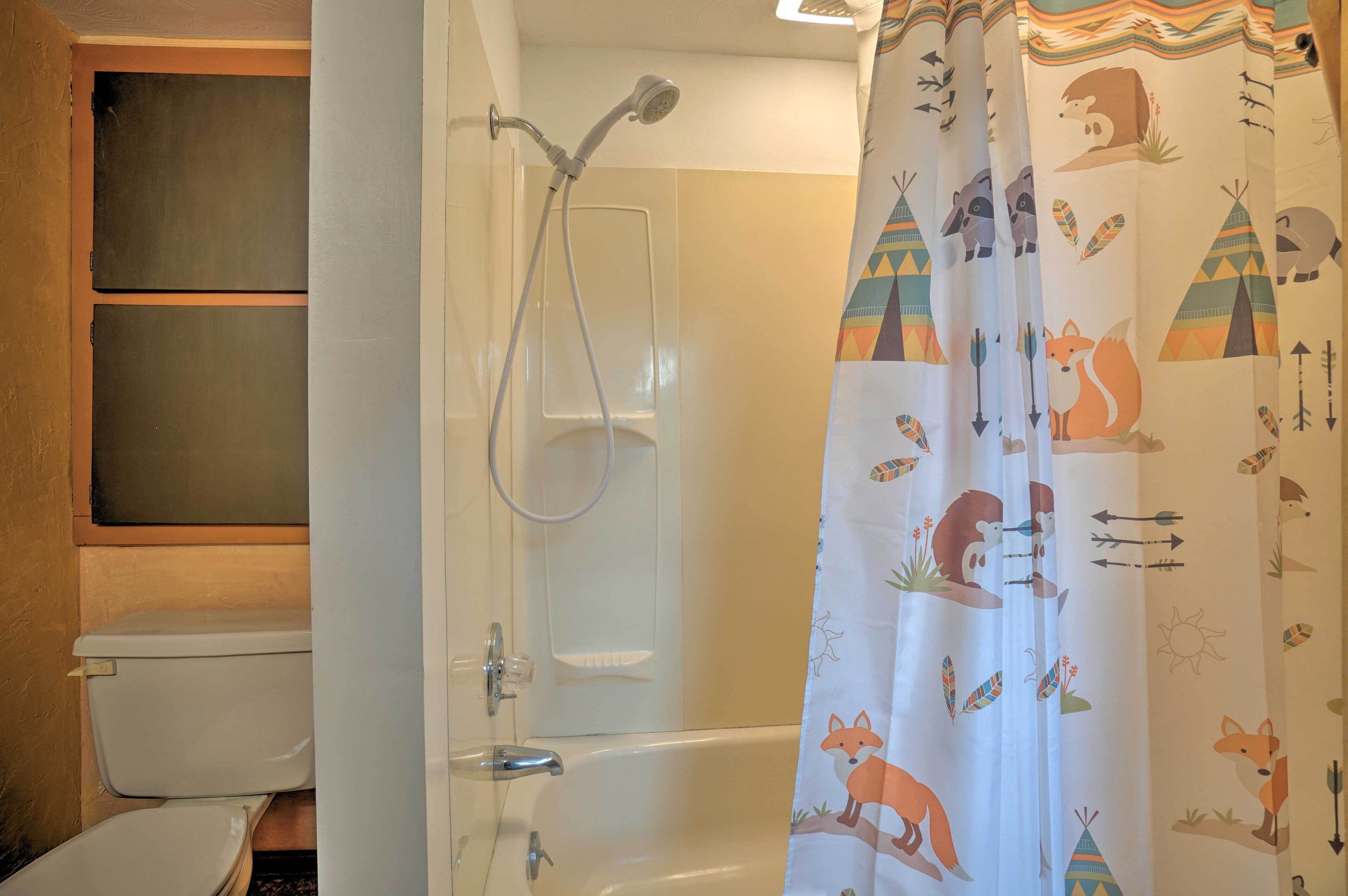 Ein Badezimmer mit Dusche, Toilette und einer Vorhang mit Tiermotiven.