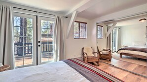 A bedroom with a large bed, a chair, and a view of the outside. - Deck & Forest Views: Munds Park A-frame Cabin (Munds Park)