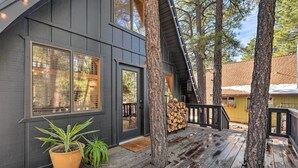 A wooden deck with a black exterior wall, large windows, and a staircase leading to a second level. - Deck & Forest Views: Munds Park A-frame Cabin (Munds Park)