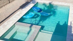 Een rechthoekig zwembad met helderblauw water, omgeven door een betegeld terras.