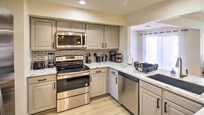 A modern kitchen with stainless steel appliances, a double sink, and light wood flooring. - Modern Lake Havasu Retreat: Lake & Mountain Views! (Lake Havasu City)