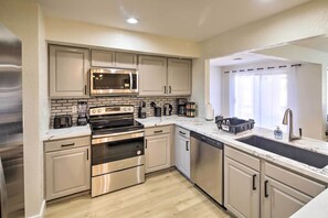 A modern kitchen with stainless steel appliances, a double sink, and light wood flooring. - Modern Lake Havasu Retreat: Lake & Mountain Views! (Lake Havasu City)