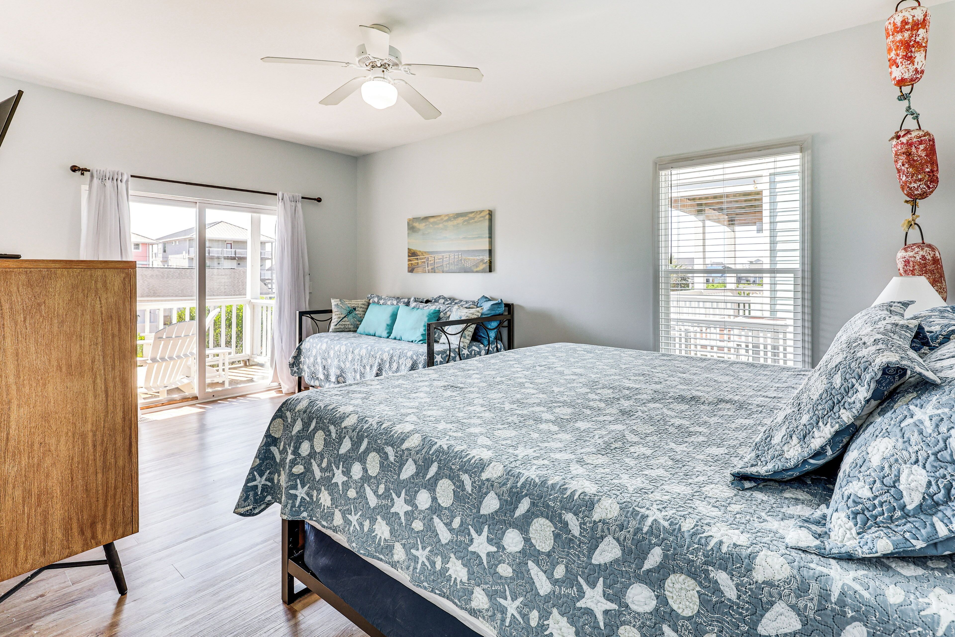A bedroom with a bed, a ceiling fan, a window with blinds, and a view of the outside.