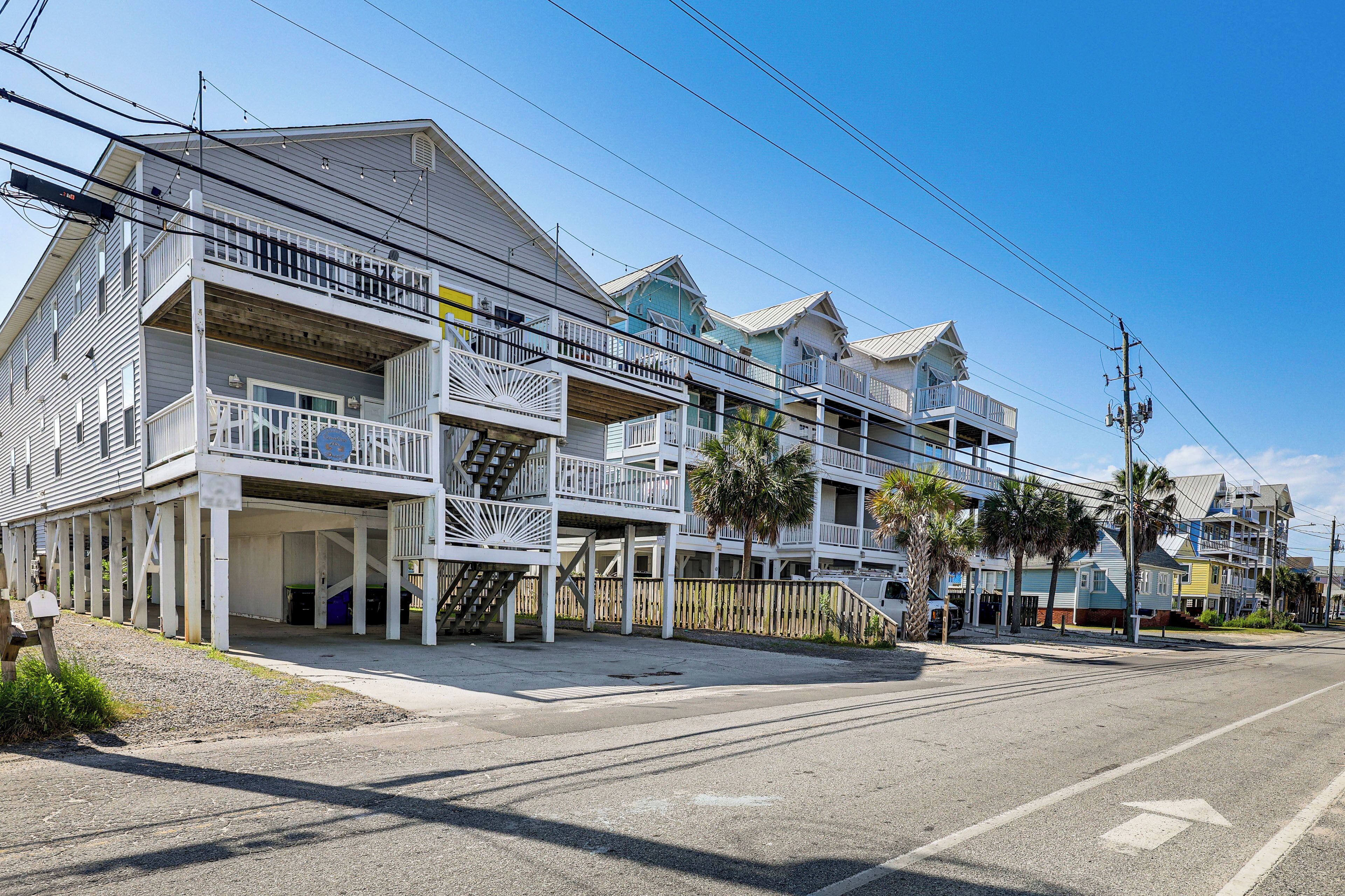 A beachfront hotel with multiple balconies, a covered walkway, and a clear view of the ocean.