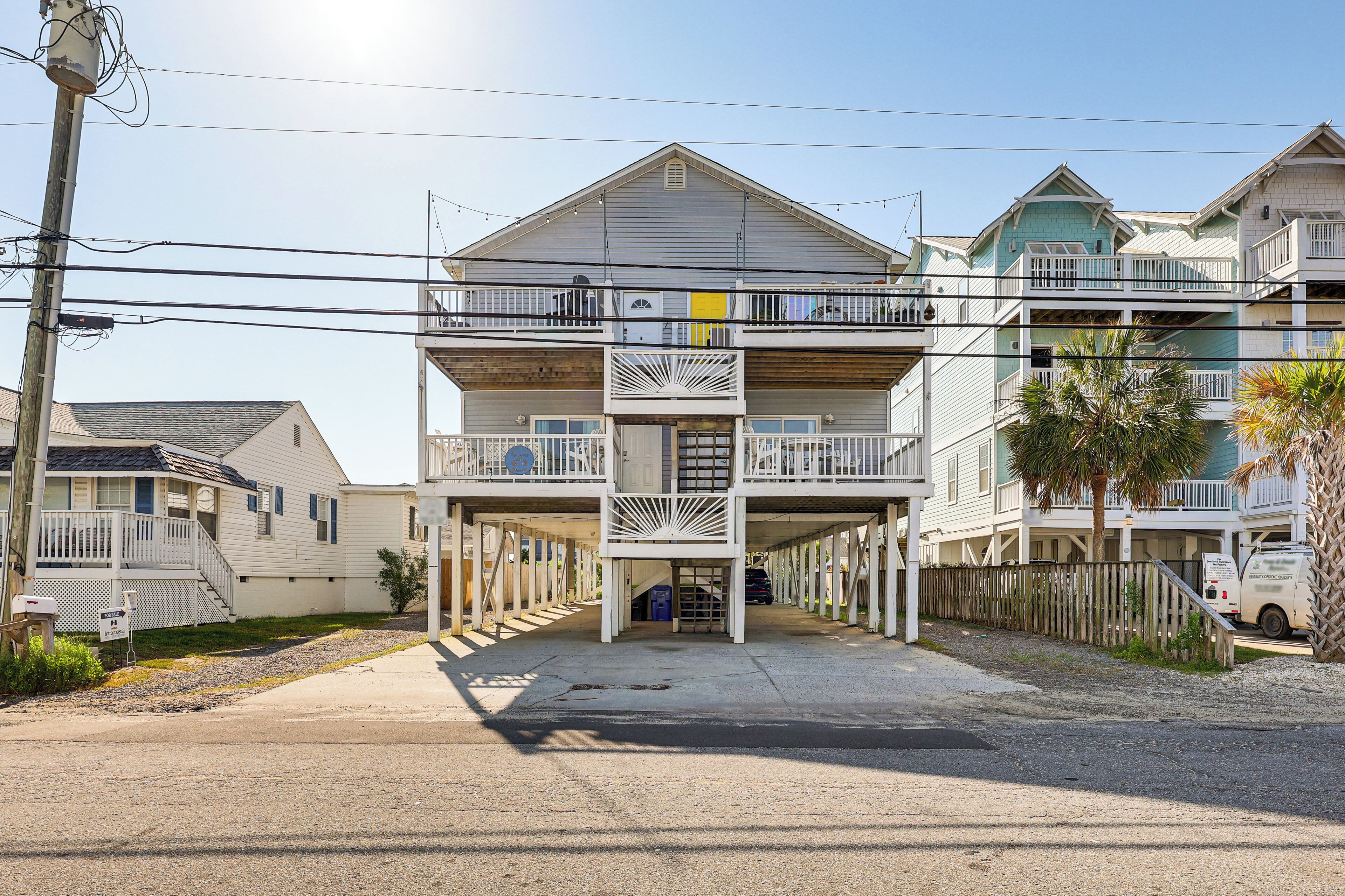A multi-story building with balconies, a covered parking area, and a utility pole.