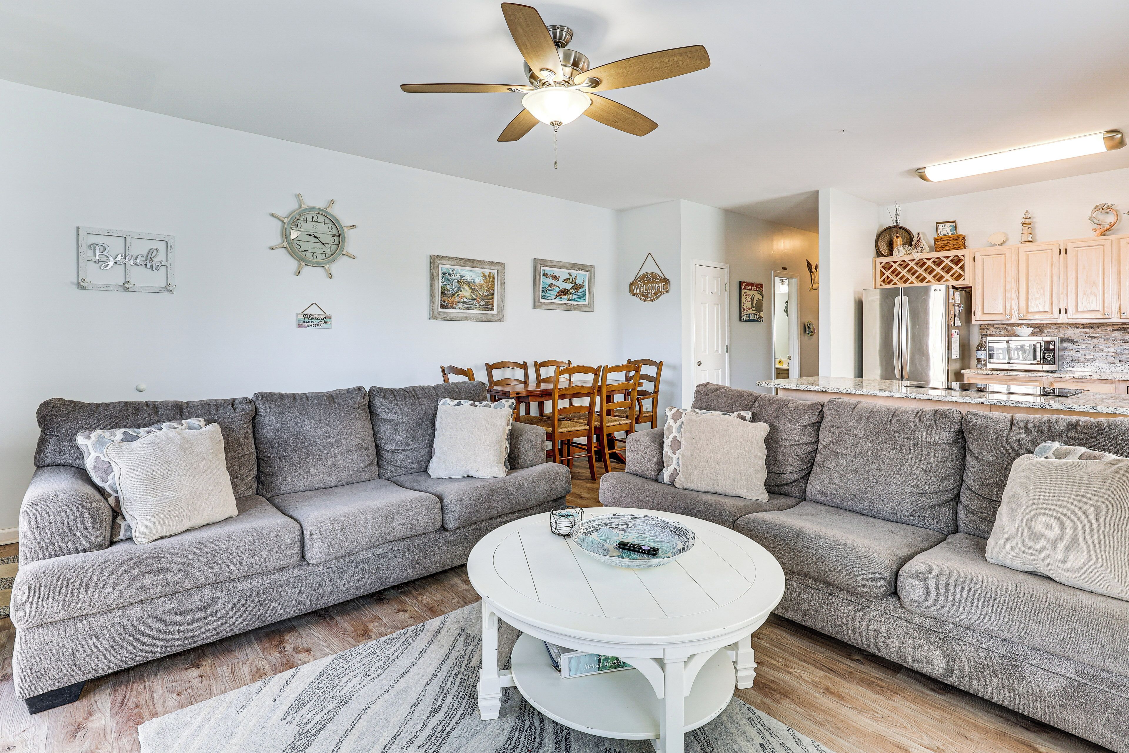 A living room with two grey sofas, a white coffee table, and a ceiling fan.