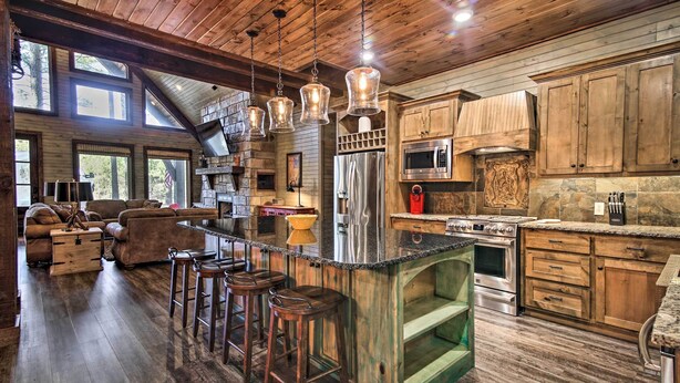 Une cuisine rustique avec des meubles en bois, un réfrigérateur en acier inoxydable et un coin bar avec des tabourets.