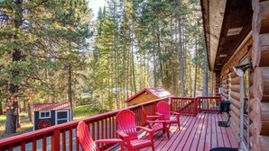 A wooden deck with red Adirondack chairs, a small wooden structure, and a forested backdrop. - 'the Innlet' - Comfy Cabin By Conkling Marina (Worley)