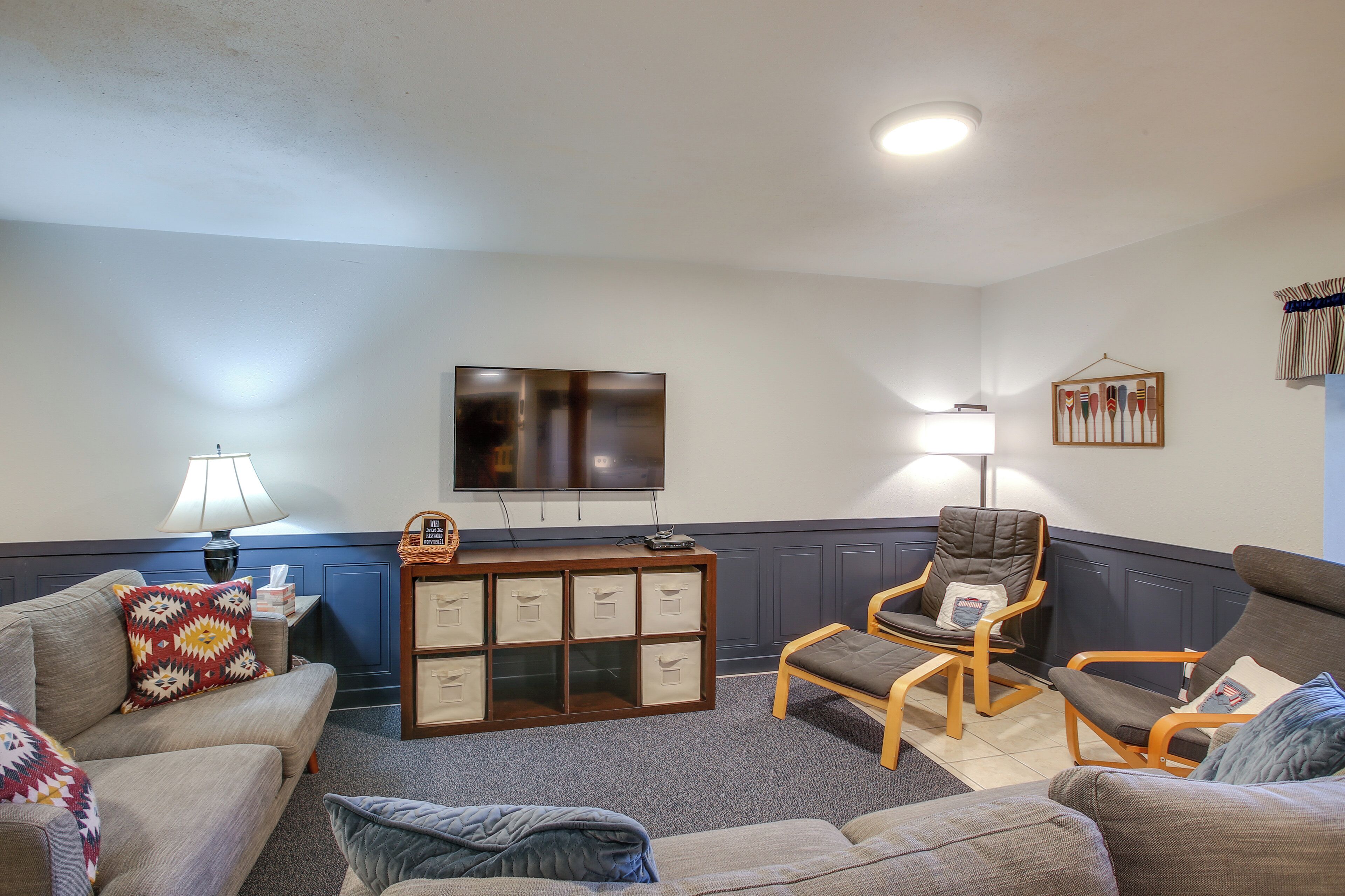 A living room with a sofa, two armchairs, a TV, a lamp, and a storage unit.
