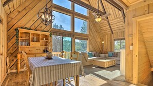 A cozy wooden cabin with a dining area, a sofa, and a bookshelf.