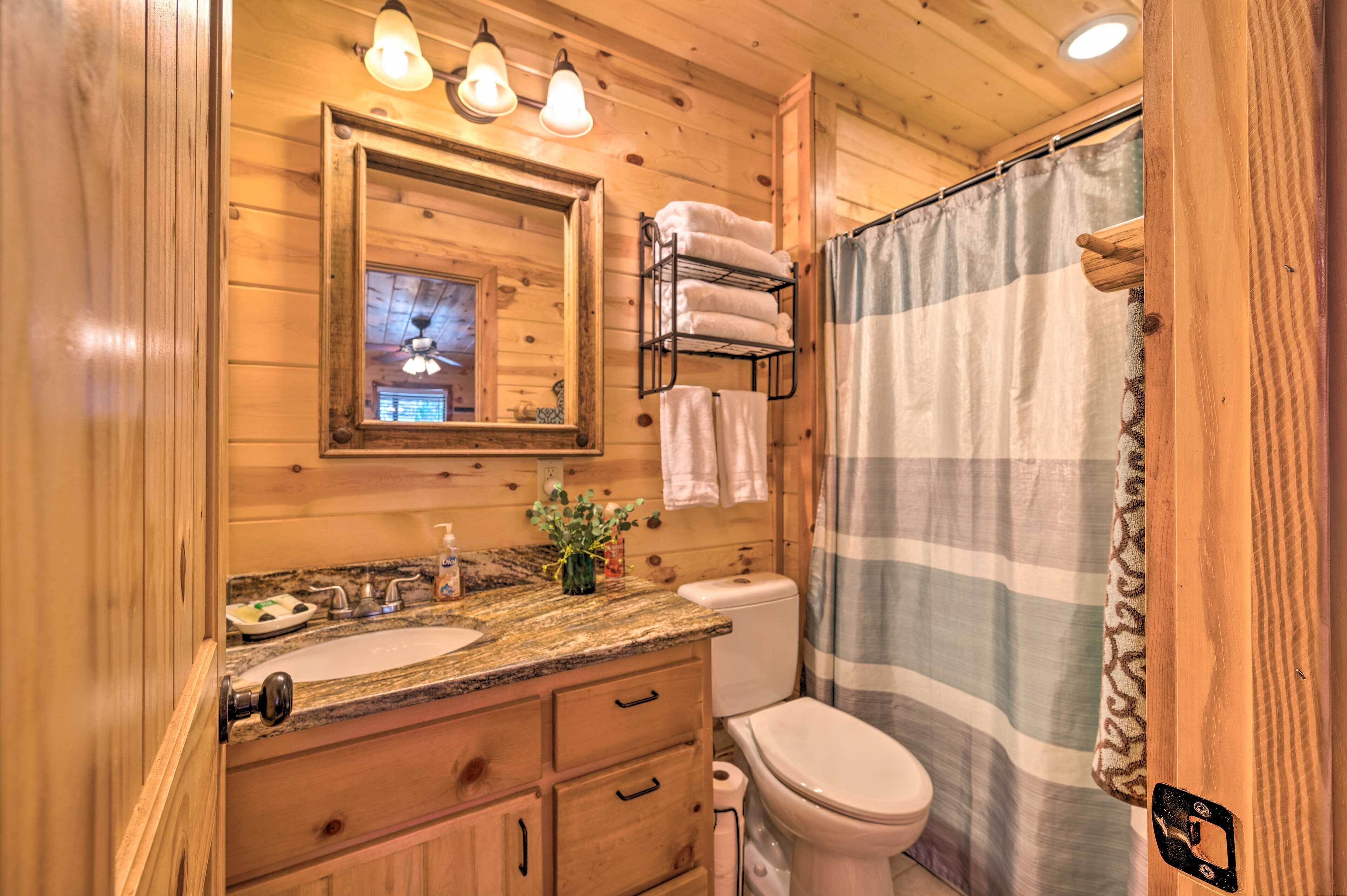 A wooden cabin bathroom with a sink, mirror, towel rack, and a shower curtain.
