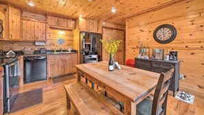 A wooden cabin kitchen with a wooden table, benches, a refrigerator, a sink, and a clock on the wall. - Hot Tub: 'little Bear's Pond' Broken Bow Cabin (Broken Bow)