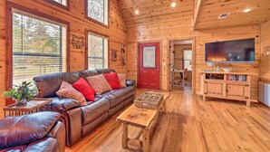 A cozy cabin interior with a leather sofa, wooden walls, and a television. - Hot Tub: 'little Bear's Pond' Broken Bow Cabin (Broken Bow)
