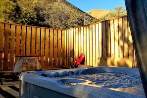 Un bain à remous dans un jardin, avec une clôture en bois et une montagne en arrière-plan.