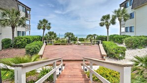 A wooden deck leading to a beach with palm trees and a clear sky. - 3 Mi to Broadway at the Beach: Oceanfront Getaway! (Myrtle Beach)
