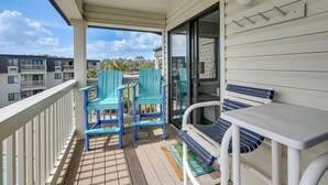 A balcony with a table and chairs, a sliding glass door, and a view of neighboring buildings. - 3 Mi to Broadway at the Beach: Oceanfront Getaway! (Myrtle Beach)