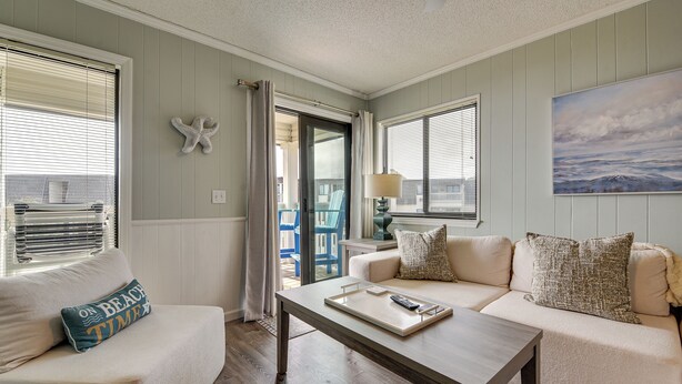 A living room with a sofa, a coffee table, and a view of the outside. - 3 Mi to Broadway at the Beach: Oceanfront Getaway! (Myrtle Beach)