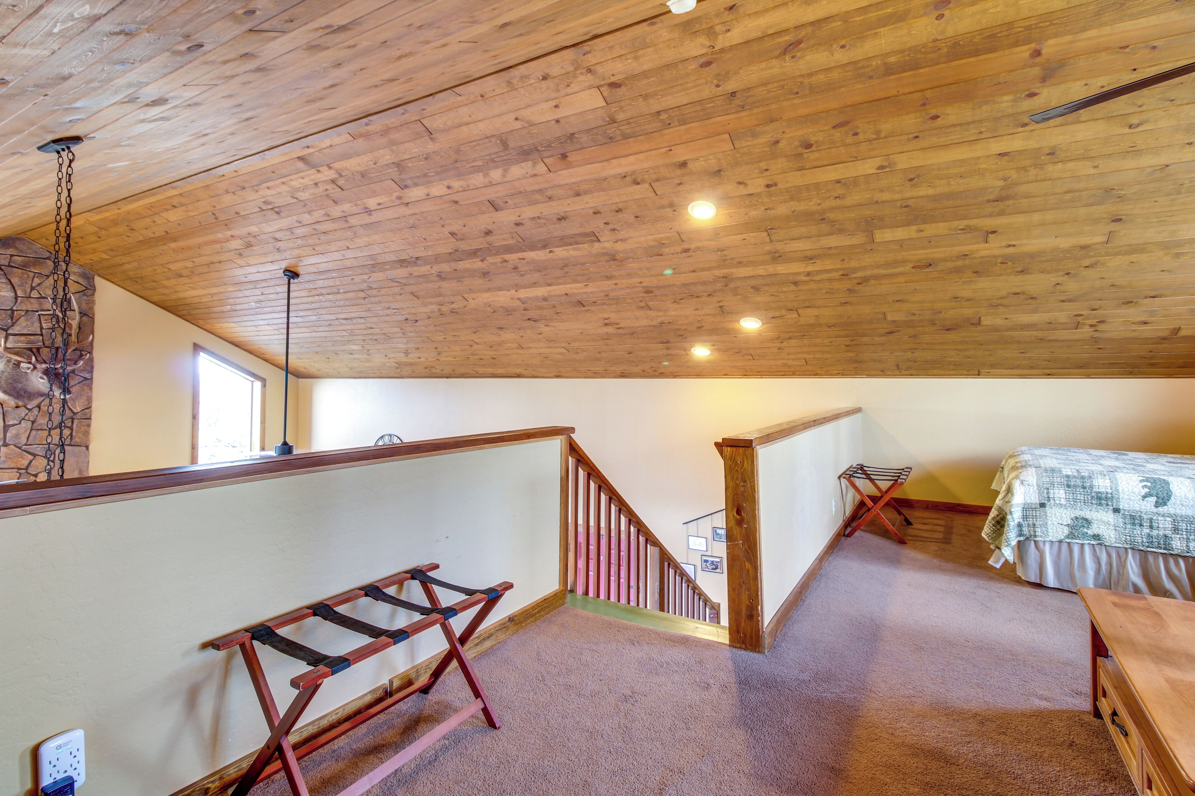 Une pièce avec un plafond en bois, un lit, un bureau, un escalier et un mur en pierre.