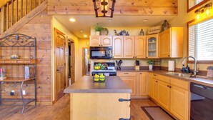 Une cuisine avec des meubles en bois, un îlot central, un four à micro-ondes et un évier.
