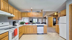 Une cuisine moderne avec des meubles en bois, un îlot central, des appareils électroménagers blancs et un ventilateur de plafond.