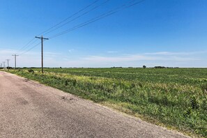 Un camino rural con campos a un lado y postes de electricidad al otro.
