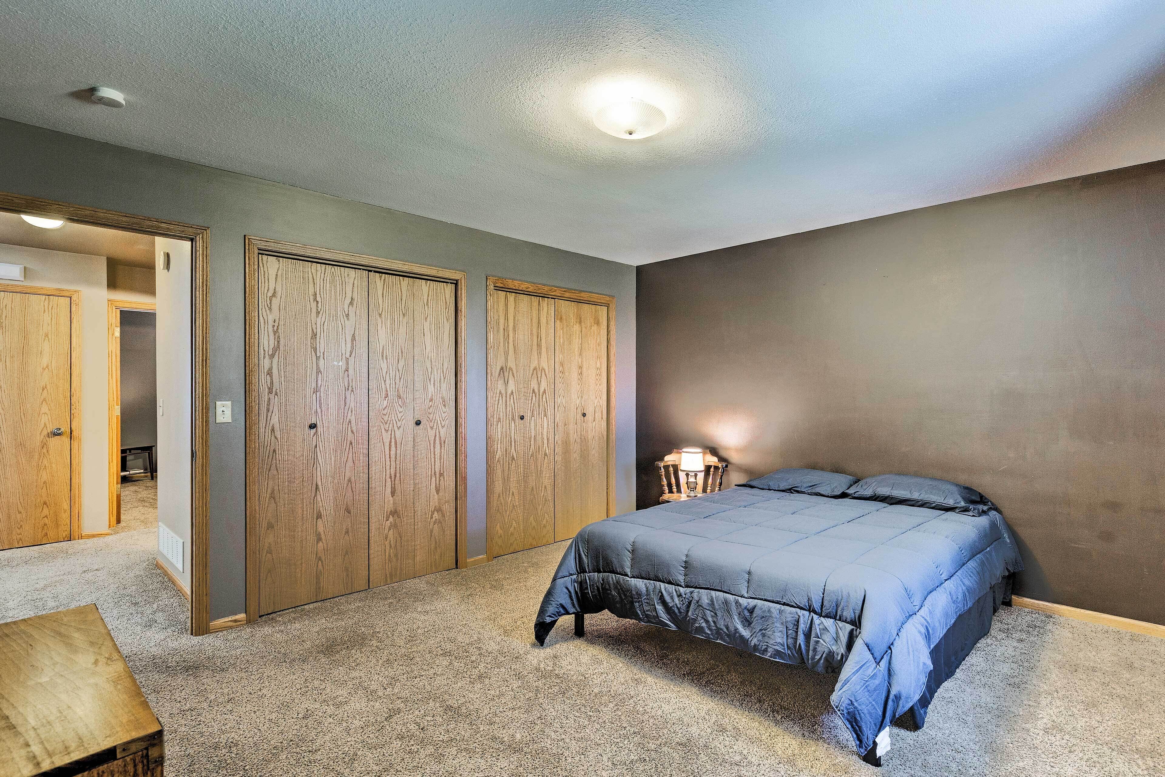 A bedroom with a bed, wooden wardrobes, a carpeted floor, and a ceiling light.