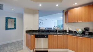 A modern kitchen with wooden cabinets, a dishwasher, and a granite countertop. - Luxurious Daytona Beach Condo w/ Resort Amenities! (Holly Hill)