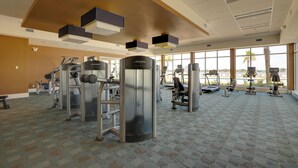 A spacious gym with various exercise equipment, large windows, and a patterned carpet. - Luxurious Daytona Beach Condo w/ Resort Amenities! (Holly Hill)