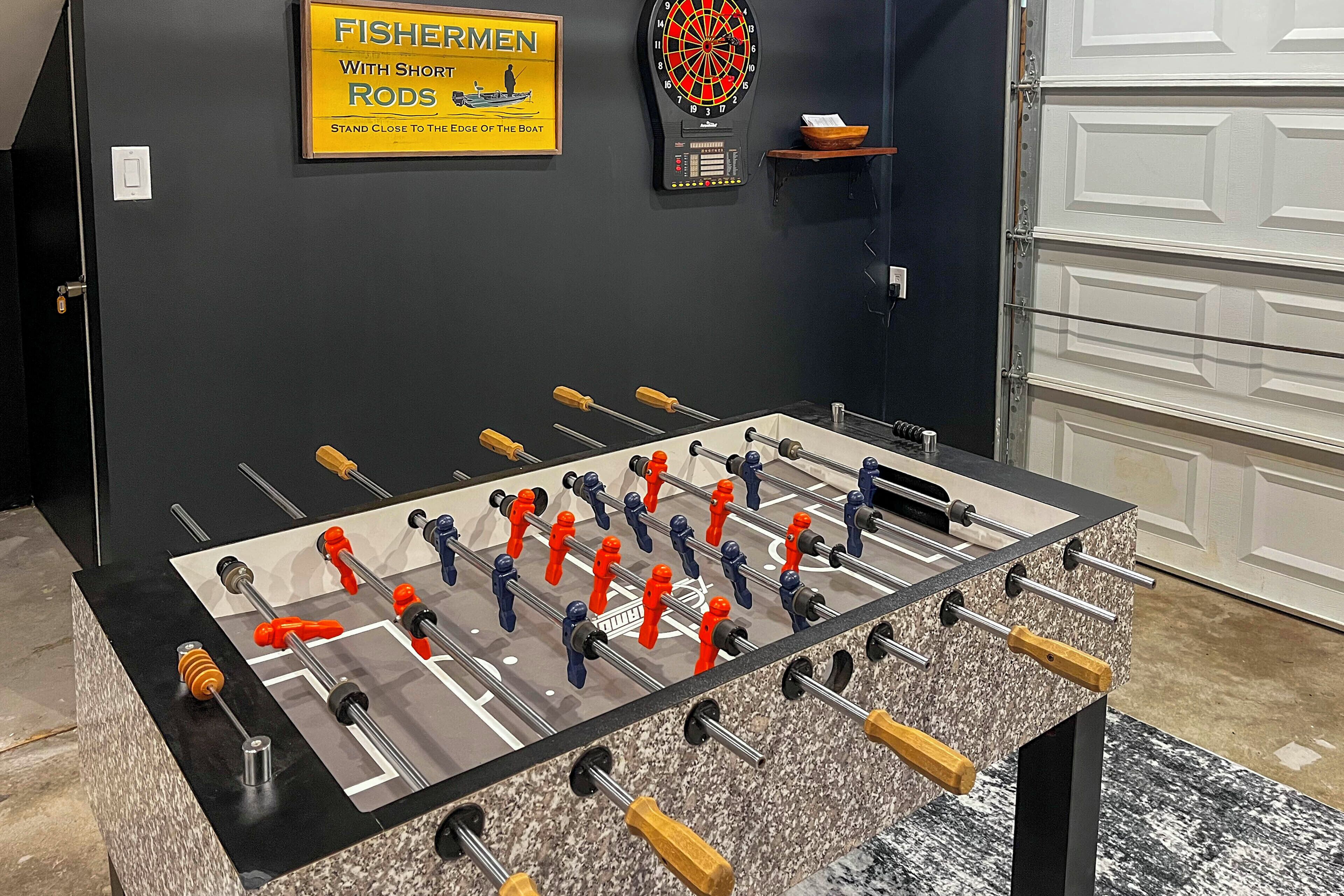 A foosball table with a dartboard and a sign on the wall.