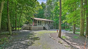 A cabin with a deck and stairs, surrounded by trees. - Home in Big Bass Lake Community: Fire Pit & Grill! (Gouldsboro)