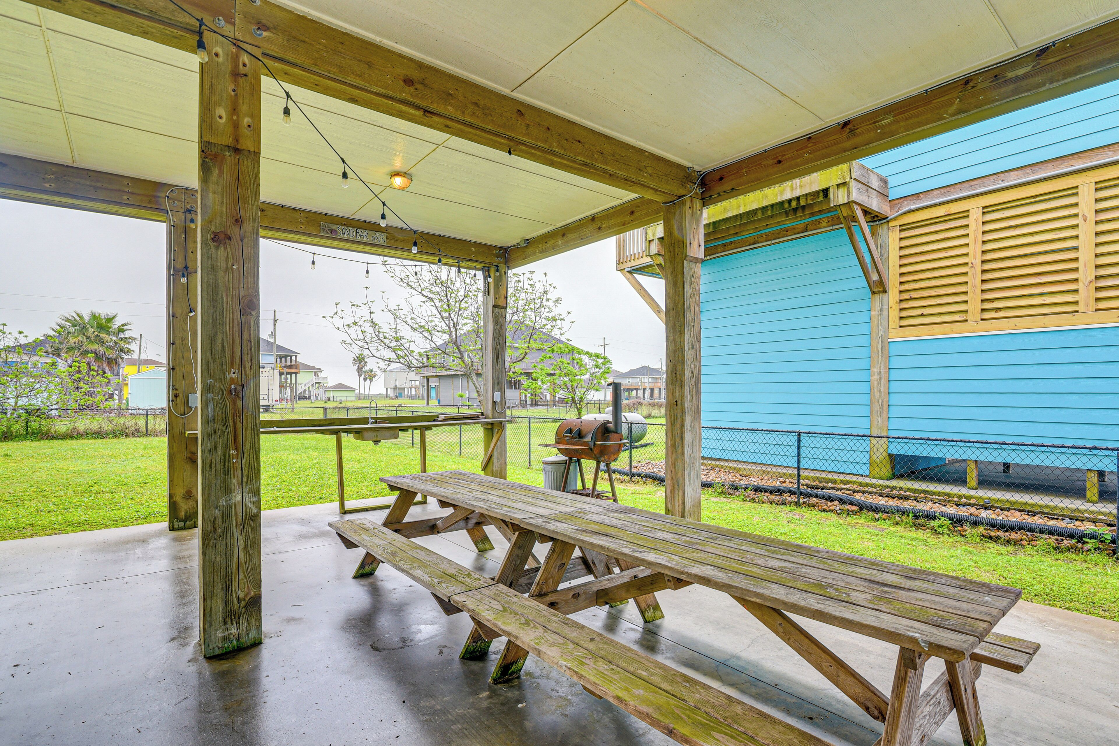 A covered picnic area with wooden benches and a barbecue grill.