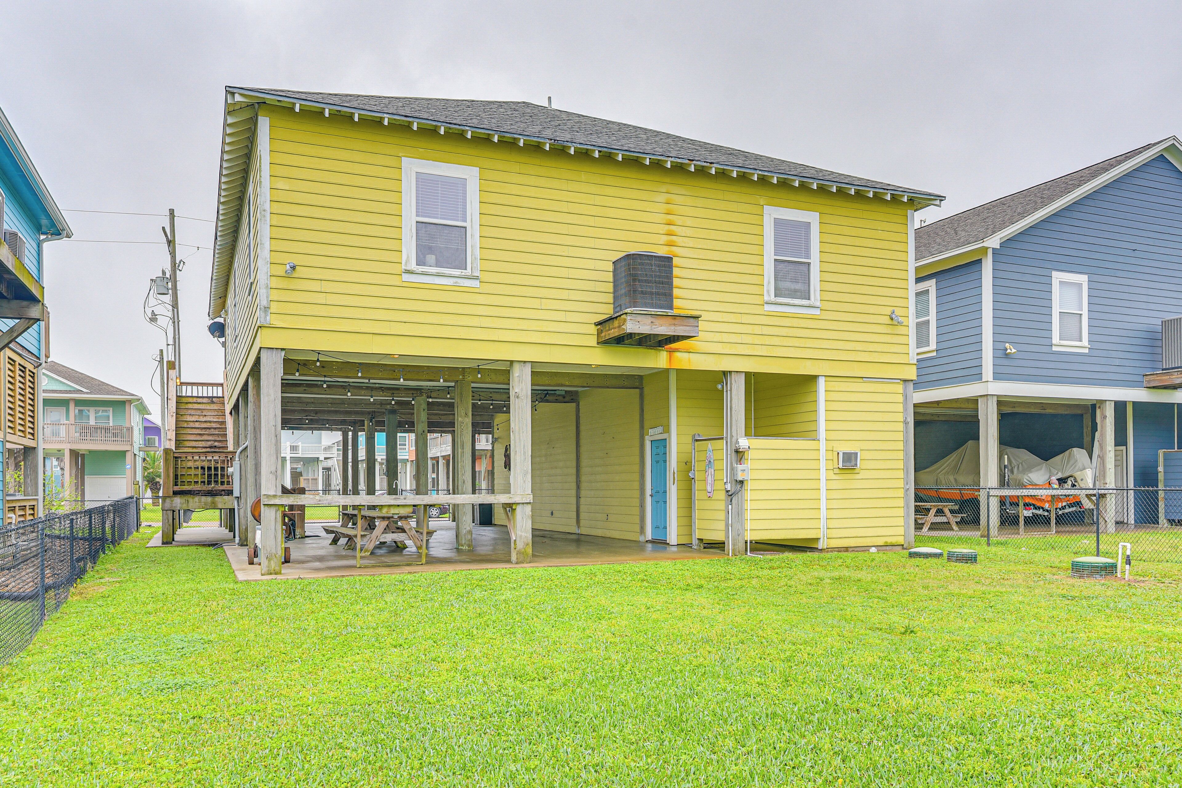 A yellow house with a covered porch and a blue house adjacent to it.