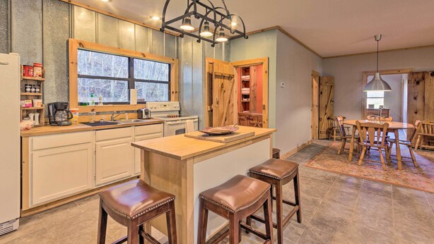 A kitchen with a central island, wooden bar stools, and a dining area with a table and chairs.