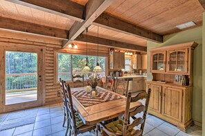 A wooden cabin interior with a dining table, chairs, and a kitchen area. - Near Vineyards: Cabin w/ Hot Tub in Pollock Pines! (Pollock Pines)