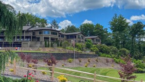 A multi-story building with a landscaped garden and a flagpole. - Beautiful Connestee Falls Home w/ Porch in Brevard (Brevard)