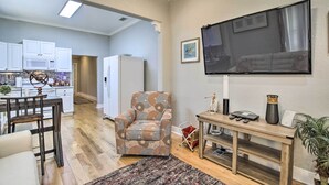 A living room with a TV, a patterned armchair, a dining area with a table and chairs, and a kitchen in the background. - Updated Ybor City House w/ Fenced Yard (Tampa)