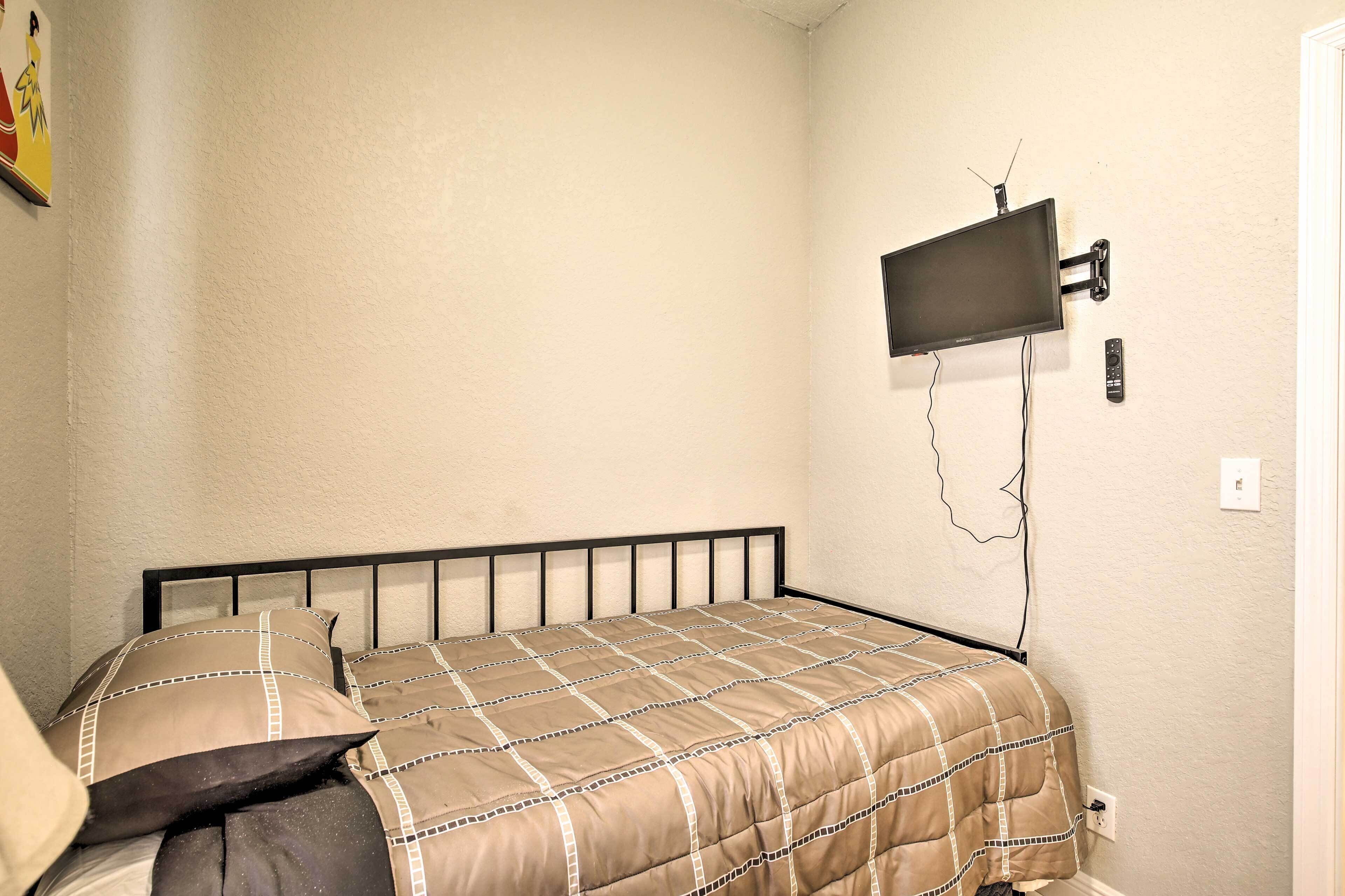 Une chambre à coucher avec un lit, un téléviseur fixé au mur et une télécommande.