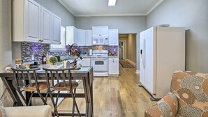 A modern kitchen with white cabinets, a microwave, and a stove. There is a dining area with a table and chairs. - Updated Ybor City House w/ Fenced Yard (Tampa)